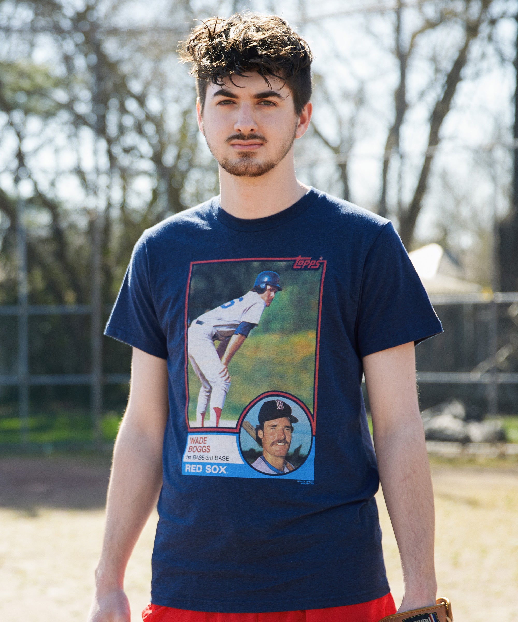 Man wearing a blue t-shirt with a Topps baseball player graphic outdoors