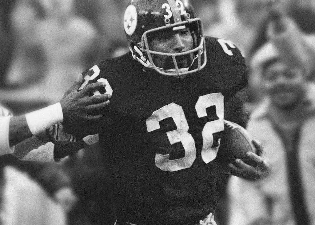 Franco Harris of the Pittsburgh Steelers eludes a tackle by the Oakland Raiders on a 42-yard run to score the winning touchdown in the American Conference playoff game. This became known as the Immaculate Reception. (AP Photo/Harry Cabluck, File)